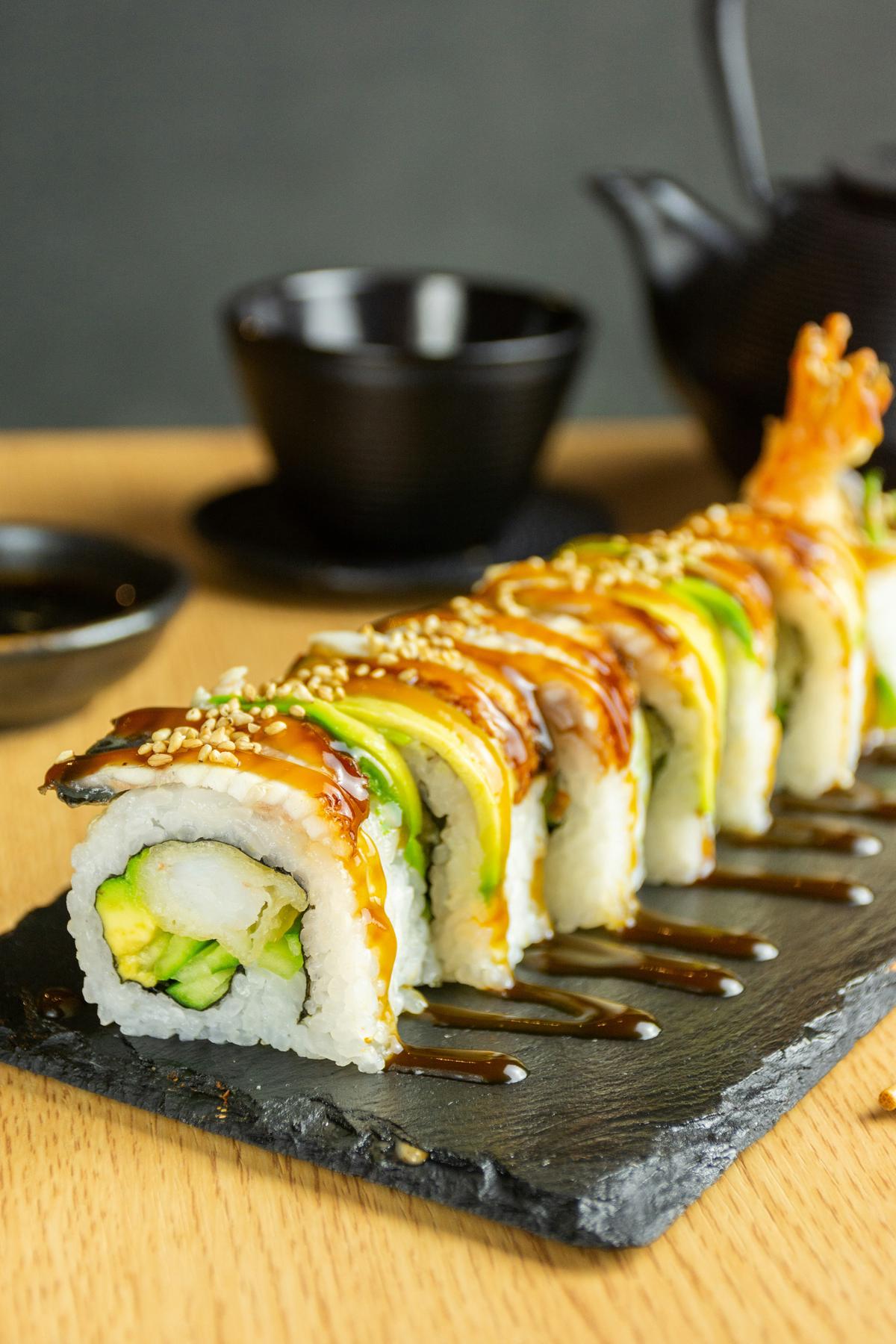 Un plato de sushi con la mano de una mujer embarazada extendiéndose hacia él, representando el disfrute del sushi durante el embarazo.